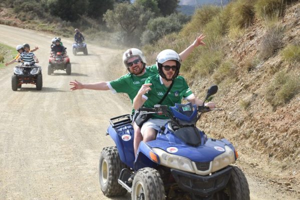 4 quads riding down a hill, the passengers are holding hands wide happily